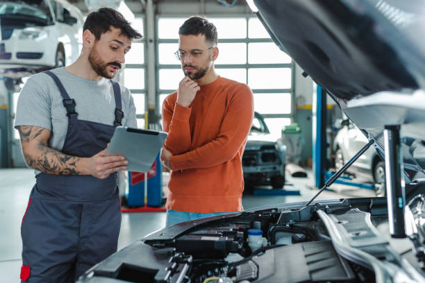 Auto mechanic explaining the problem to the customer while using digital tablet in a repair shop